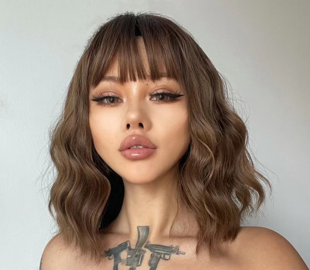 Trilumity curly wig with bangs in light brown, shoulder-length wavy style worn by a model